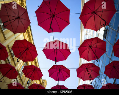 Basso angolo di visione della Red ombrelloni sospesi il sovraccarico con edifici su entrambi i lati ed un cielo blu; Belgrado e Vojvodina, Serbia Foto Stock