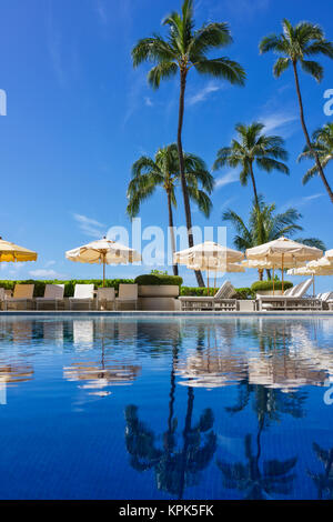 Piscina Halekalani a Waikiki con palme e ombrelloni riflessa nell'acqua; Honolulu Oahu, Hawaii, Stati Uniti d'America Foto Stock