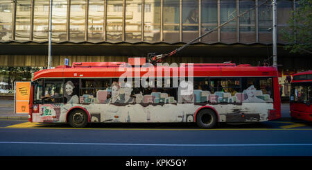 Un bus elettrico sulla strada con artwork sul lato raffigurante i volti delle persone; Belgrado e Vojvodina, Serbia Foto Stock