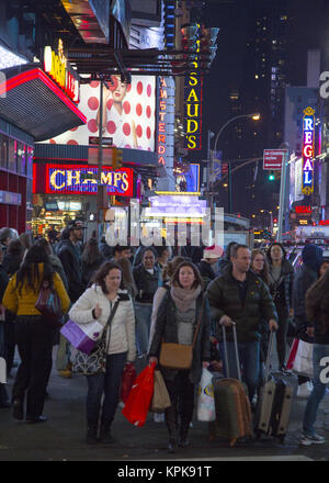 La folla di turisti con le valigie e borse per lo shopping a piedi sulla West 42nd Street in Times Square District durante la stagione di festa di Natale a Manhattan, New York City. Foto Stock