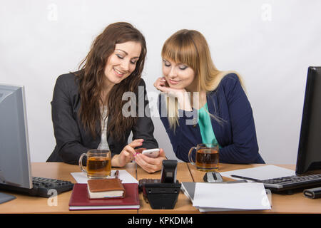 Ufficio di due ragazze discutere questioni personali e di bere il tè alla scrivania Foto Stock