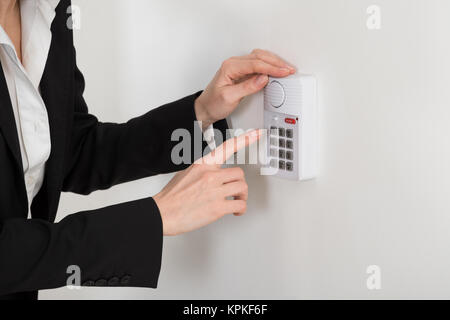 Donna mano, premendo il pulsante sul sistema di sicurezza Foto Stock