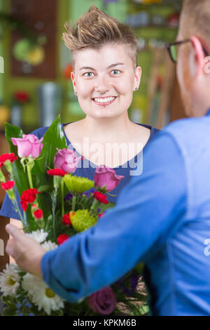 Donna sorridente nel negozio di fiori disposizione acquisti Foto Stock