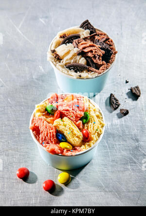 Vista aerea di due coloratissimi dessert congelato tazze e rabboccato con cookie e pezzetti di cioccolato contro un sfondo testurizzata Foto Stock