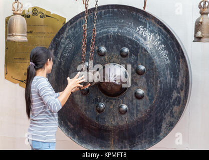 Bangkok, Tailandia. Giovane donna che colpisce il Gong durante la salita alla cima di Wat Saket (Phu Khao Thong), il Golden Mount. Un nipplo Gong. Foto Stock