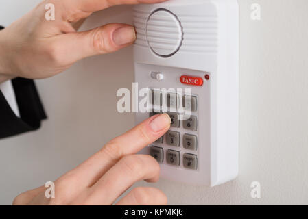 Donna mano, premendo il pulsante sul sistema di sicurezza Foto Stock