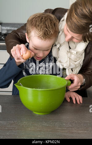 Ragazzo e madre rendendo la pasta per le torte Foto Stock