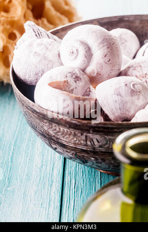 Close Up della collezione di conchiglie di mare in vaso decorativo nel blu dipinto di superficie in legno con spugna naturale in background - Nautica Spa a tema Vita ancora con spazio di copia Foto Stock