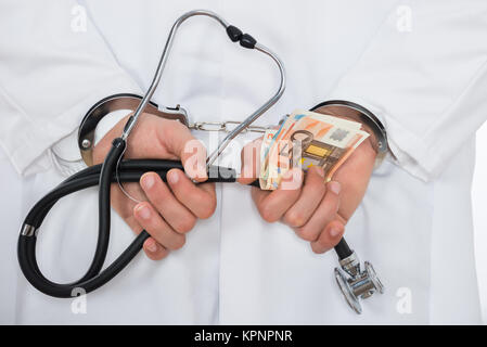 Medico con banconote in euro e manette Foto Stock