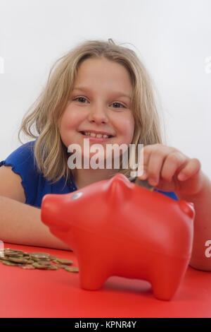 Modello di rilascio , Maedchen, 8 Jahre, fuettert Sparschwein - ragazza con salvadanaio Foto Stock