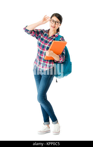 Smart studente graziosa ragazza con bicchieri guardando fotocamera a sorridere e portante la scuola studiano libri isolati su sfondo bianco. Foto Stock