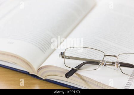 Chiudere i bicchieri e un libro sulla scrivania Foto Stock