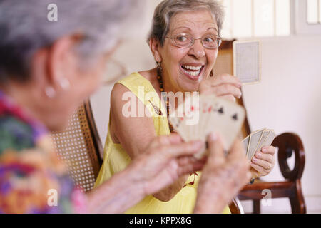 Il vecchio donna gode giocare gioco di carte in ospizio Foto Stock