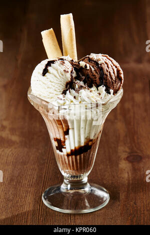 Cioccolato e gelato alla vaniglia spruzzata con salsa di cioccolato e servita con due fette di silicio laminati in un lungo il vetro per un rinfrescante dessert estivo Foto Stock