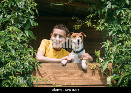 Ragazzo sorridente con il cane su treehouse Foto Stock