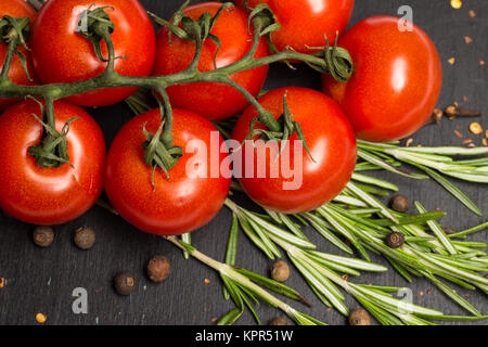 Il ramo di ciliegia pomodori maturi, rosmarino fresco, il pepe della Giamaica, cibo fotografia Foto Stock