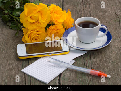Tazza di caffè, telefono, bouquet di rose e portatile con maniglia Foto Stock