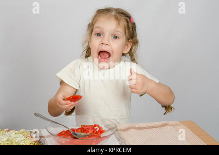 Bambina con la bocca aperta tenendo una grande fetta di pomodoro Foto Stock