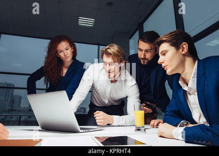 Maschio e femmina la gente di affari intorno al computer portatile in ufficio Foto Stock