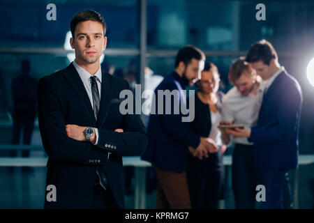 Titolare di una piccola azienda in piedi con le braccia incrociate con il dipendente in background Foto Stock