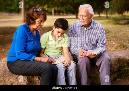 Il nonno e la nonna aiutando ragazzo con compiti Foto Stock