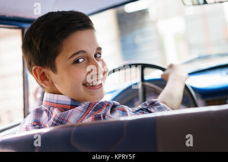 Ritratto bambino tenuto lezione di guida nella vecchia auto sorridente Foto Stock