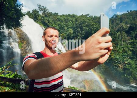 Giovani turistica prendendo un selfie contro Wachirathan cascata. Chiang Mai Provincia, Thailandia. Foto Stock