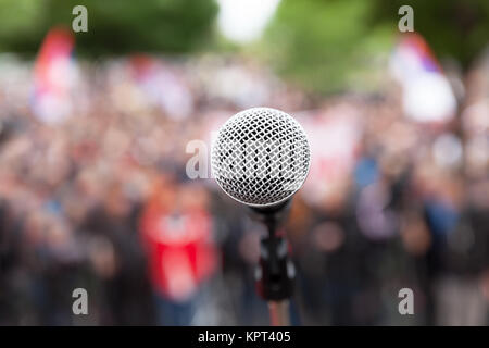 Microfono a fuoco contro pubblico sfocata. Politica dei rally. Foto Stock
