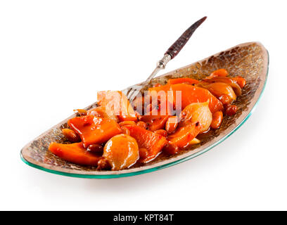 Ancora la vita di Tajine tradizionale piatto di verdure fatta con arancio brillante verdure in salsa e servito in lungo e stretto piatto moderno con forcella su sfondo bianco con spazio di copia Foto Stock