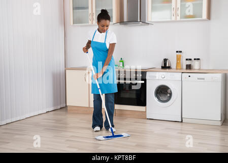 Bidello femmina pavimento con straccio In Cucina Foto Stock