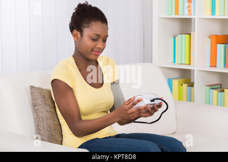 Donna controllando la pressione del sangue a casa Foto Stock