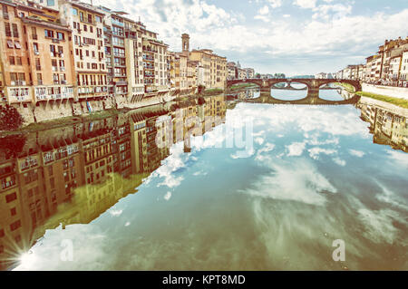 Edifici vecchi e bellissimo Ponte Santa Trinita specchiata nel fiume Arno, Firenze, Toscana, Italia. Destinazione di viaggio. Foto giallo filtro. Foto Stock