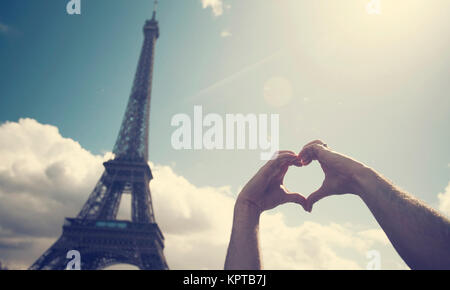 Amore a Parigi - mani formando una forma di cuore davanti alla Torre Eiffel Foto Stock