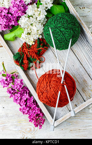 Palle di filati di lana per maglieria e rami di fiori lilla Foto Stock