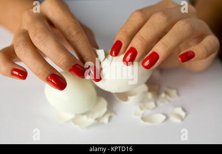 Mani femminili con una bella manicure pulire l'uovo di pollo. Il cibo. Foto Stock