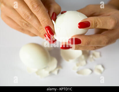 Mani femminili con una bella manicure pulire l'uovo di pollo. Il cibo. Foto Stock