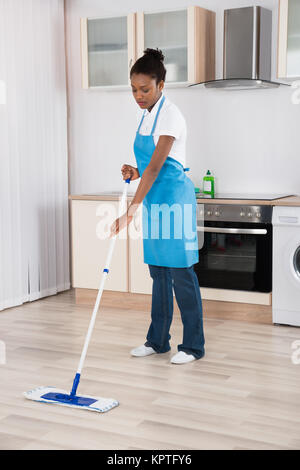 Bidello femmina pavimento con straccio In Cucina Foto Stock