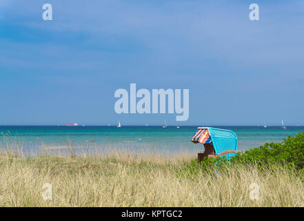 Bellissima spiaggia sedia nelle dune con il Mar Baltico navi a vela in background, Germania Foto Stock