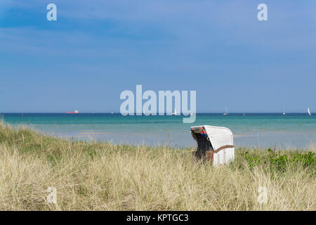 Bellissima spiaggia sedia nelle dune con il Mar Baltico navi a vela in background, Germania Foto Stock