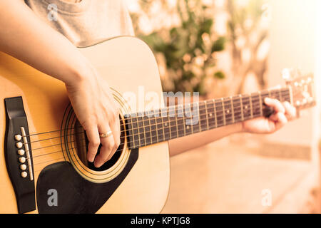 Donna con le mani in mano suonare la chitarra acustica con stile vintage Foto Stock