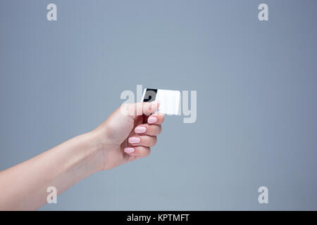 La scheda in una femmina di mano è su sfondo grigio Foto Stock