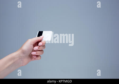 La scheda in una femmina di mano è su sfondo grigio Foto Stock