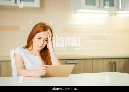 Stanco donna soffre mal di testa mentre si lavora da casa con la compressa Foto Stock