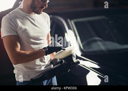 Lavoratore meccanico a preparare per la lucidatura di auto dal buffer di alimentazione macchina Foto Stock