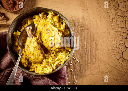 Vista dall'alto sopra il tavolo con la pentola di culinarie Indiane che serve di salsa speziata biryani di pollo con spezie e spazio di copia Foto Stock