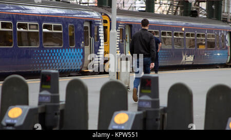 Barriere di biglietteria, il treno e il commuter sulla piattaforma presso la stazione centrale di Glasgow, Glasgow, Scozia Foto Stock