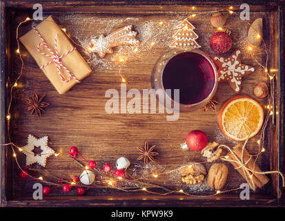 Vin brulé o punzone in vetro, biscotti di Natale, asciugare le arance e le luci sul buio rustico sfondo vintage, vista dall'alto, di confine. Concetto di natale. Foto Stock