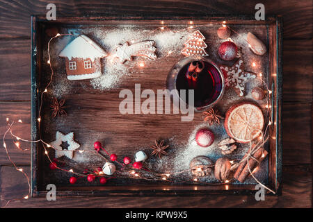 Vin brulé o punzone in vetro, biscotti di Natale, asciugare le arance e le luci sul buio rustico sfondo vintage, vista dall'alto, di confine. Concetto di natale. Foto Stock