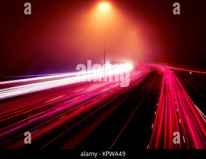 Abstract artistico semaforo percorsi su una trafficata autostrada in ora di punta su una notte nebbiosa, Highway 401, Toronto, Ontario, Canada. Foto Stock