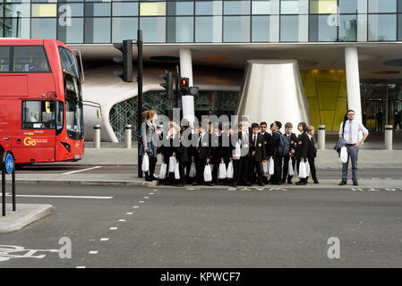 Gruppo di bambini in uniforme scolastica con il loro insegnante di attendere a un attraversamento pedonale a Londra Inghilterra Ottobre 2017 Foto Stock